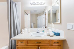 Un baño con lavamanos, espejo y armarios de madera.