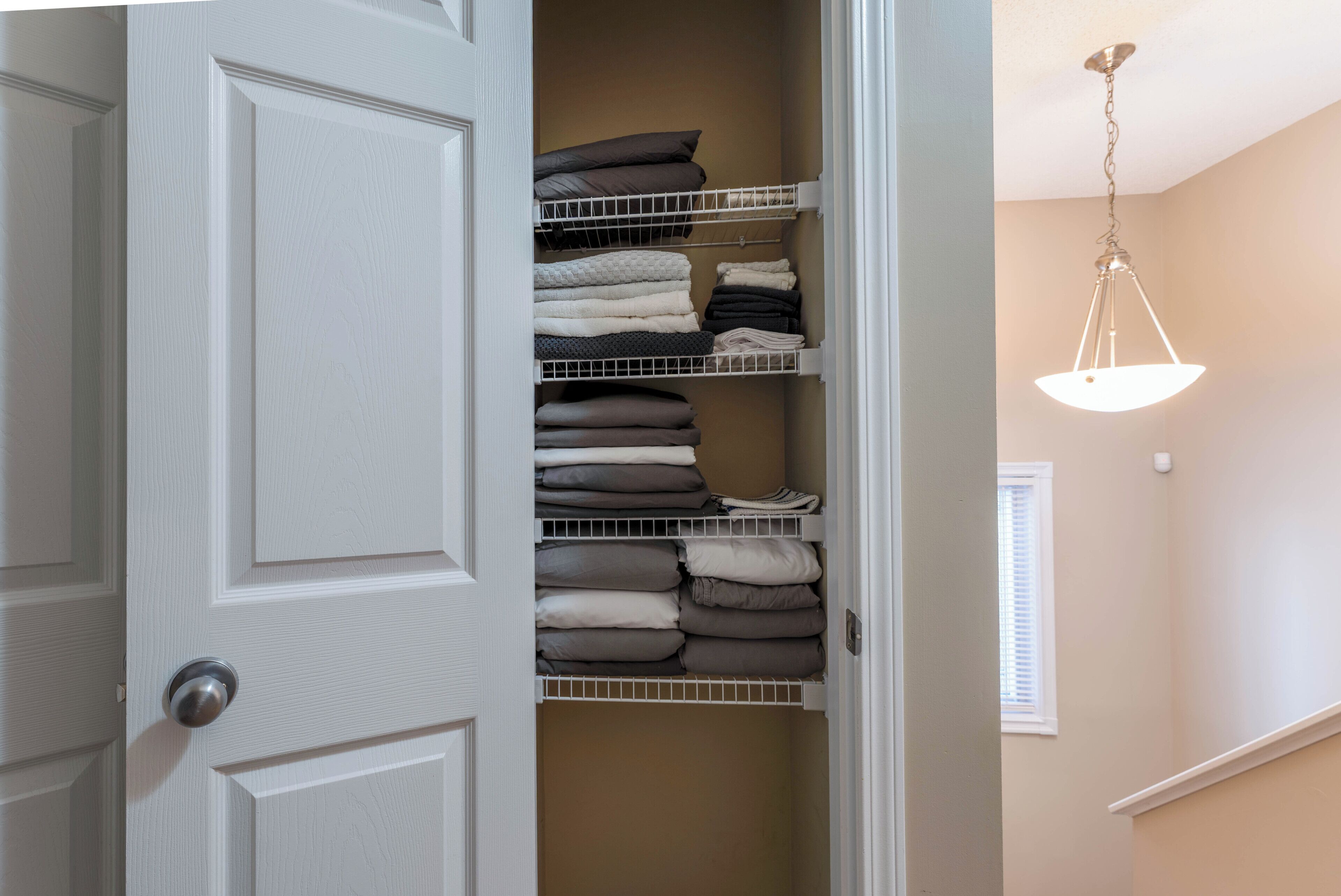 A closet with shelves and hanging space, a door with a silver handle, and a ceiling light fixture.