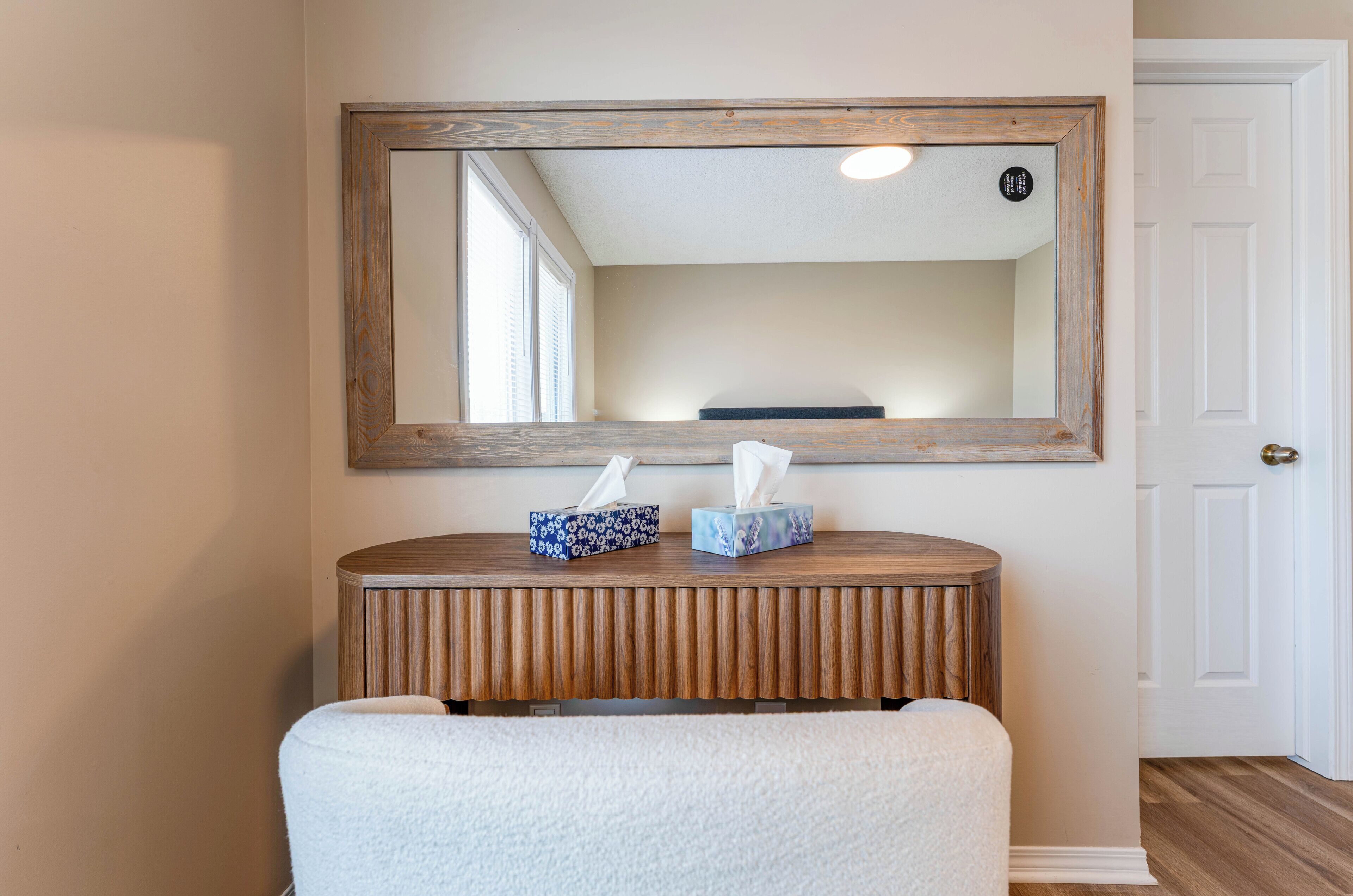 A wooden console table with two tissue boxes and a mirror above it.