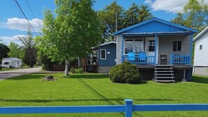 Ett bostadshus med en veranda på framsidan, en liten trädgård framför huset och ett blått staket.