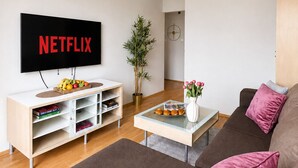 Una sala de estar con televisor, una mesa de centro, un sofá y una estantería.