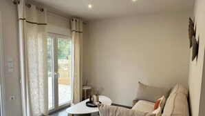 A modern living room with a sofa, a coffee table, and a view through large glass doors. - Rouli's Houses by All About Paxos (Paxos)