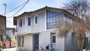 Un edificio a due piani con un balcone, una bicicletta parcheggiata di fronte e un albero sullo sfondo.