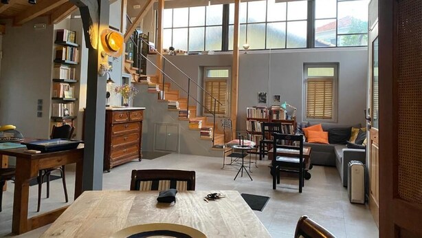 Un'ampia zona giorno con una scala in legno, librerie e un tavolo da pranzo.