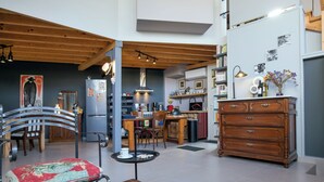 Una cucina moderna con travi in legno, una zona pranzo con sedie in metallo, un tavolino da caffè con sottopiattino e un settimino in legno.