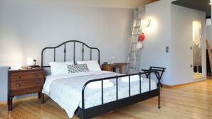 Una camera da letto con un letto, una cassettiera in legno e una scala appoggiata al muro.