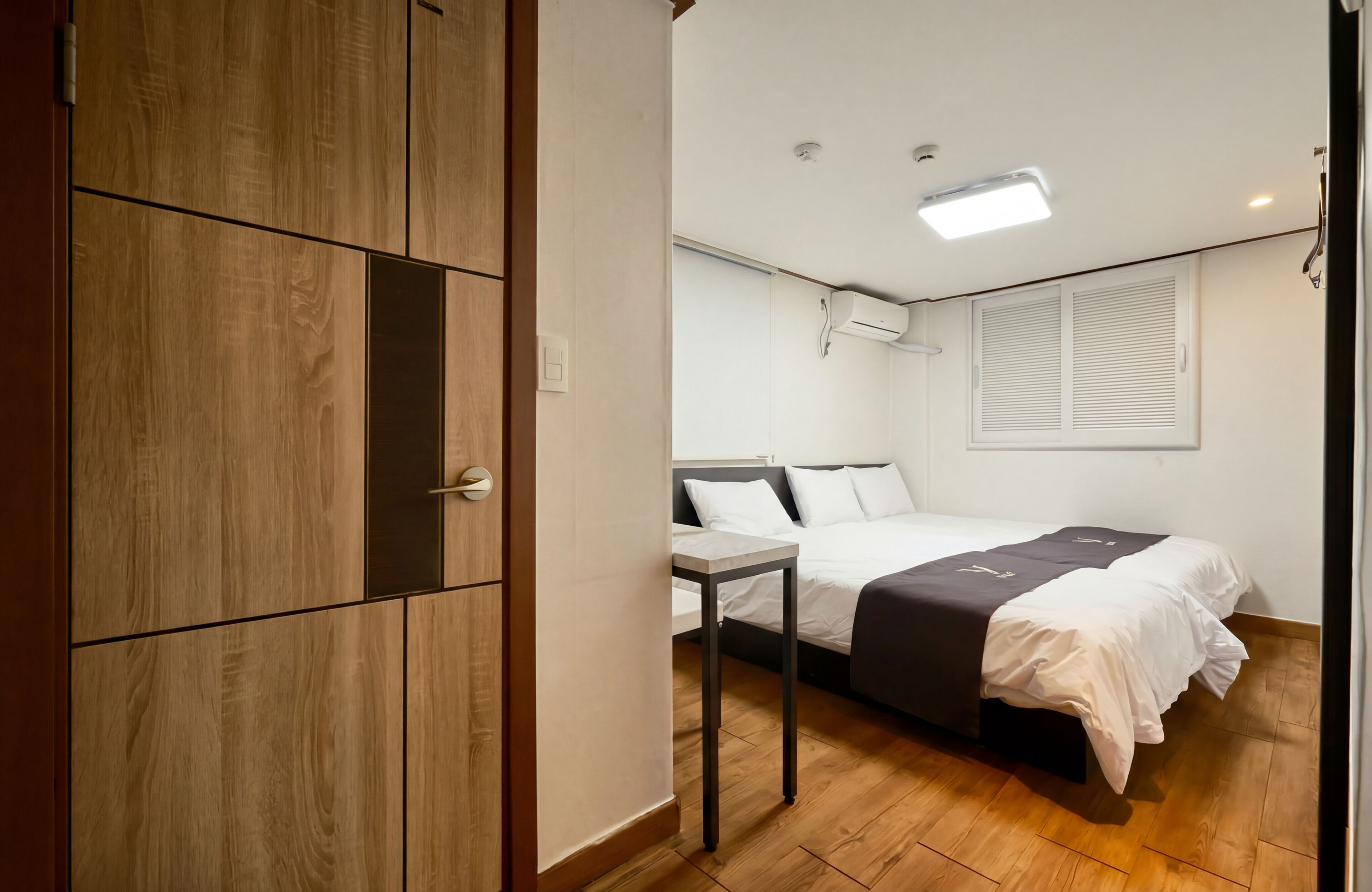 A bedroom with a bed, bedside table, wardrobe, and a window with blinds.