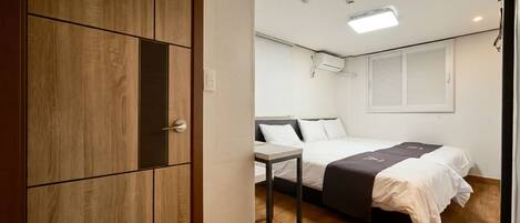 A bedroom with a bed, bedside table, wardrobe, and a window with blinds.