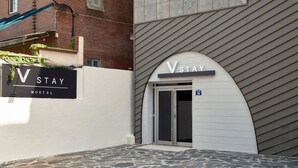 Et hostel med et skilt, der viser 'VSTAY HOSTEL', og en dør med nummeret '30' over.