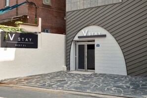 Un hostal con un letrero que dice 'VSTAY HOSTEL' y una puerta con el número '30' encima.