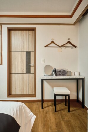 A room with a wooden door, a small table with a white bench, and two wall-mounted hangers.