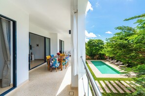 Ein Balkon mit Pool, Gartenmöbeln und Blick ins Grüne.