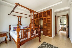 Ein Bett mit Himmelbett und Holzbalken, ein Holzschrank mit Klappläden und ein kleiner Nachttisch.