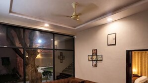 A modern living room with a sectional sofa, a coffee table, and a ceiling fan. - Misti Pool And Resort (Jaipur)