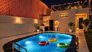 A swimming pool with three inflatable rings, a 'MISTI' sign, and a bar area with a sink and plants. - Misti Pool And Resort (Jaipur)