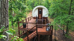 A wooden deck leading to a covered cabin in a forest. - Lux Glamping Wagon - with A/C, WIFI, Full Bath (Sevierville)