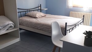 Et soveværelse med seng, stol, skrivebord og en radiator.
