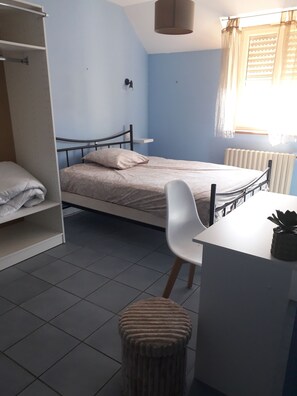 Ein Schlafzimmer mit Bett, Stuhl, Schreibtisch und Heizkörper.
