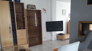 En stue med fjernsyn, sofabord, sofa og skab.