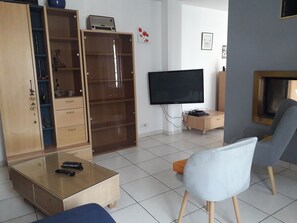 Ein Wohnzimmer mit Fernseher, Couchtisch, Sofa und Schrank.
