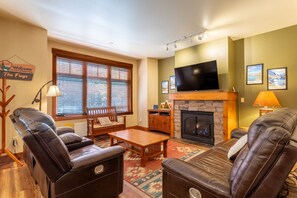A living room with leather recliners, a wooden coffee table, a fireplace, a flat-screen TV, and a sign reading 'Welcome to our homestead The Freys.' - Beautiful 2/2 Golf/Ski Condo-Garage, Jacuzzi, BBQ! (Mammoth Lakes)