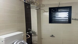 A bathroom with a toilet, washing machine, and a window with blinds. - Charming 1-bedroom apartment in the heart of Ruighar (Ruighar)