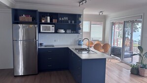 Una cocina moderna con microondas integrado, refrigerador de acero inoxidable, armarios azul oscuro y una isla grande con pileta.