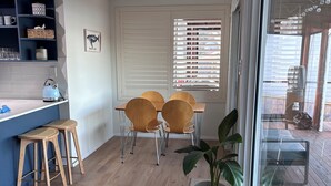 Una cocina moderna con encimera azul, taburetes de madera y un comedor con cuatro sillas.