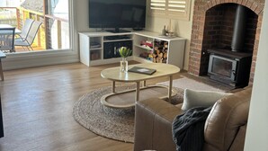 Una sala de estar con televisor, chimenea y balcón.