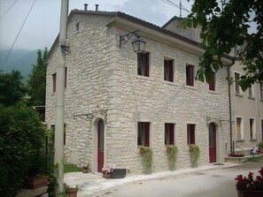 A stone building with multiple windows and doors, a street lamp, and potted plants. - Beautiful apartment for 5 guests with A/C, WIFI, pool, TV, veranda and panoramic view (Miane)