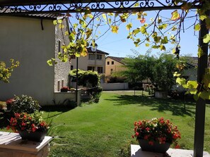 Un patio con un césped cuidado, plantas en macetas y un edificio de fachada de piedra.