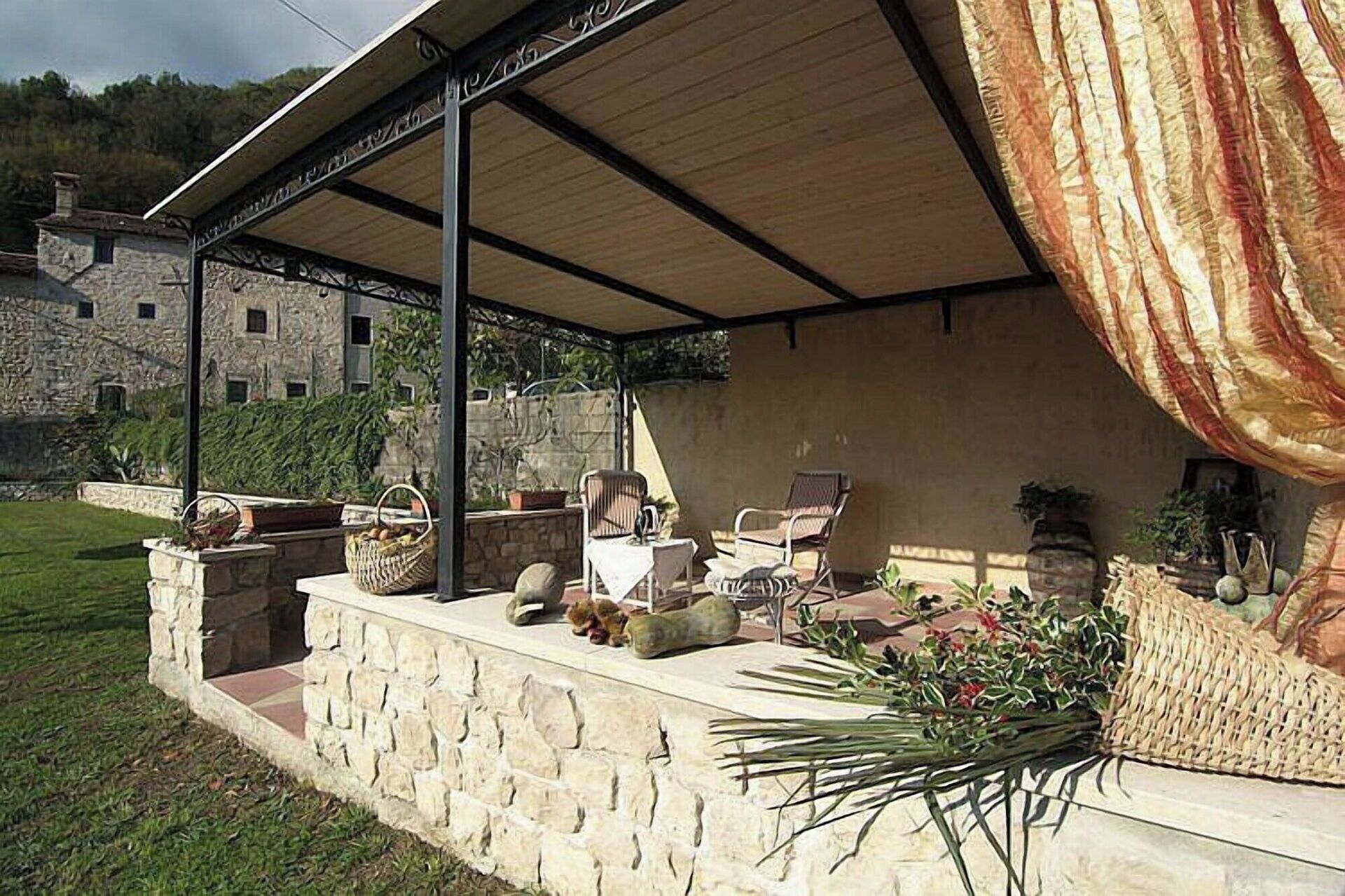 Un espace extérieur abrité, aménagé avec des murs en pierre, des paniers en osier et des plantes en pot.