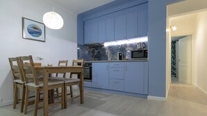 A modern kitchen with blue cabinets, a dining table with chairs, and a hanging light fixture.