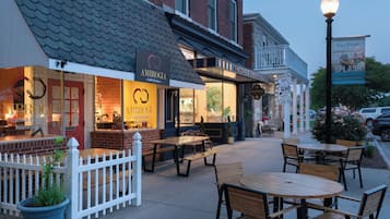Un restaurant avec une terrasse, une clôture blanche en bois et une enseigne portant le nom « AMBROGIA ».
