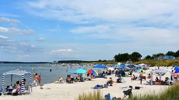 Une plage avec des gens, des parasols et des chaises de plage.