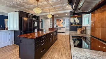 Une cuisine moderne dotée d’un îlot central, de meubles de rangement aux couleurs sombres et d’un plan de travail en bois.