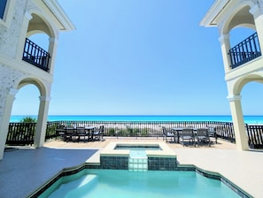 Ein Pool mit Blick auf den Strand, Sitzgelegenheiten im Freien und einem klaren Himmel.
