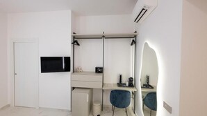 Una camera moderna con scrivania, sedia, TV e condizionatore.