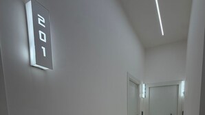 Un corridoio moderno con un display digitale che mostra il numero 201, una tastiera e un pavimento illuminato.