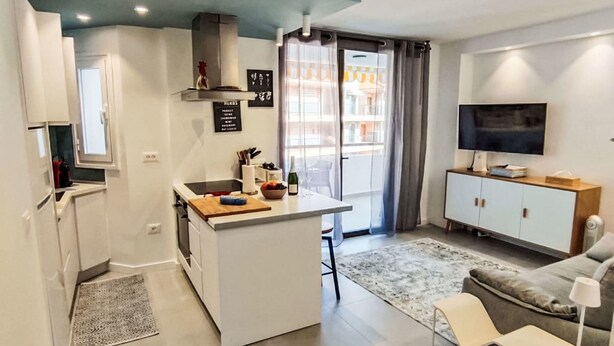A compact living space with a kitchenette, a dining area, a sofa, a TV, and a balcony with curtains. - ruhige, charmant renovierte Wohnung, Terrasse, P by Interhome (Los Cristianos)