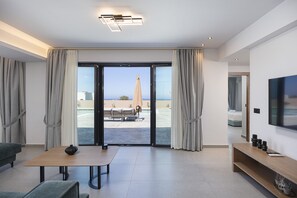 Ein modernes Hotelzimmer mit Schiebetür zu einem Außenbereich, einem Flachbildfernseher, einem Holztisch und einer Couch.