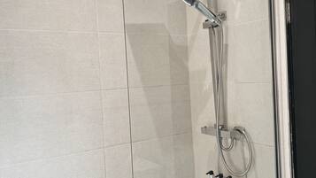 A modern bathroom with a glass-enclosed shower, a white bathtub, and a chrome showerhead.