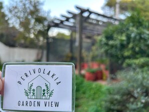 A sign with 'PERIVOLAKIA GARDEN VIEW' text and a house with plants. - Perivolakia Garden View - Rafina Stay Near Airport (Rafina-Pikermi)