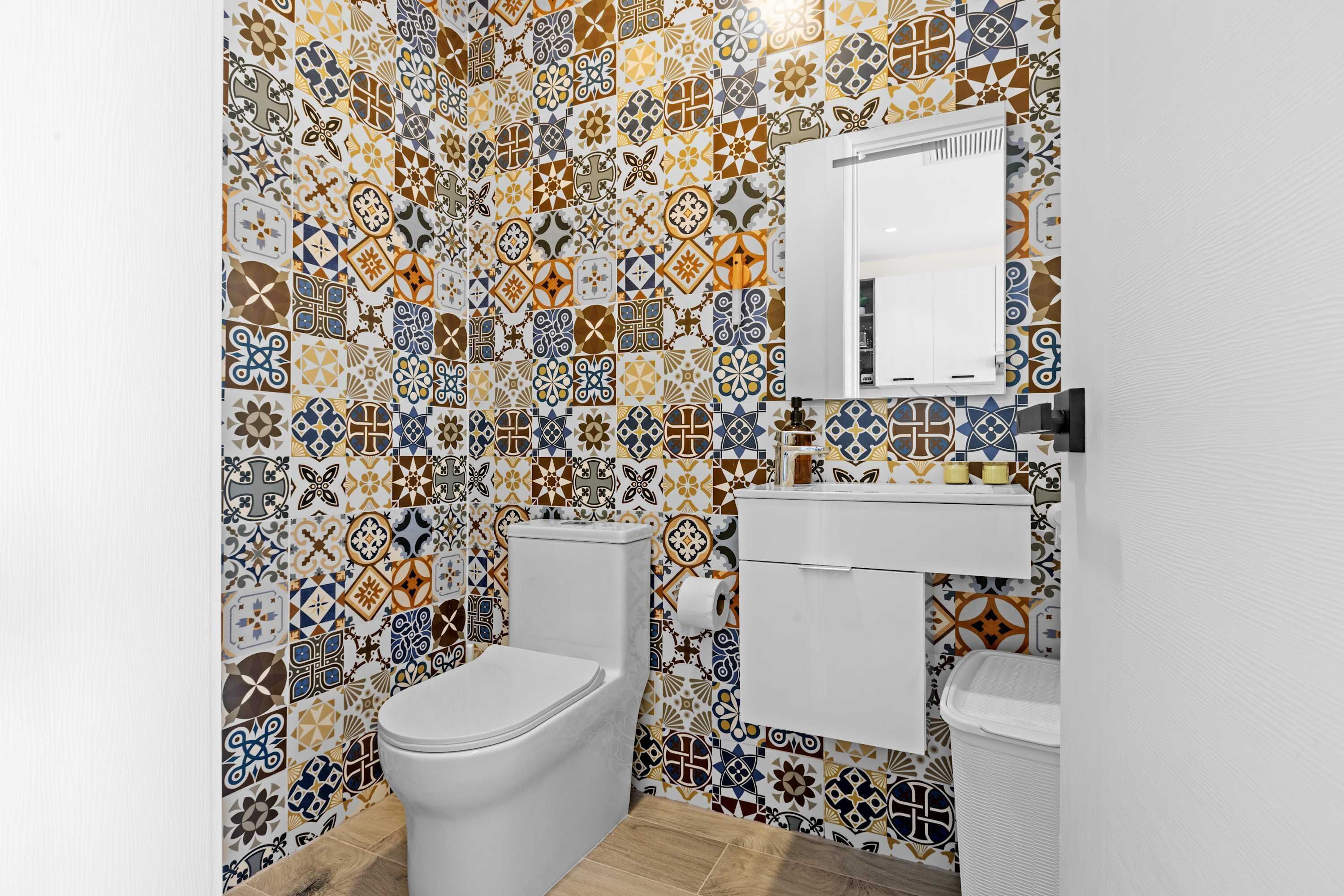 Une salle de bain avec un mur carrelé, des toilettes, un lavabo et un miroir.