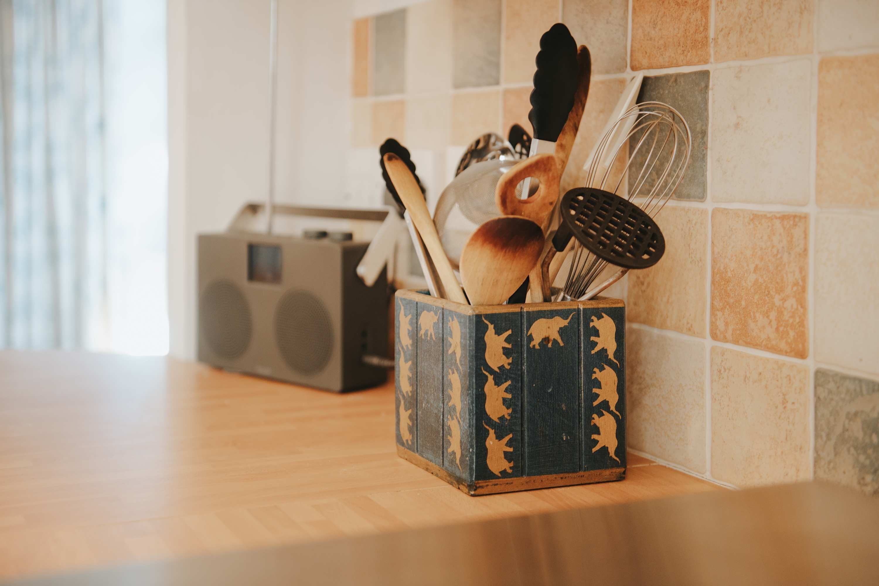 A kitchen counter with a wooden cutting board, a radio, and a spice rack with utensils.