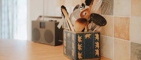 A kitchen counter with a wooden cutting board, a radio, and a spice rack with utensils.