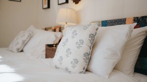A neatly made bed with white bedding and patterned pillows, a bedside table with a lamp, and a wall with framed pictures. - Traditional Cottage Near Richmond Yorkshire Dales (Richmond)