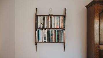 Una estantería con libros y una botella de vidrio en la pared.