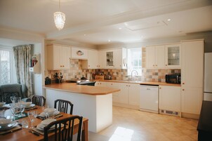 A modern kitchen with white cabinetry, a central island, and a dining area with chairs and a table set for four.