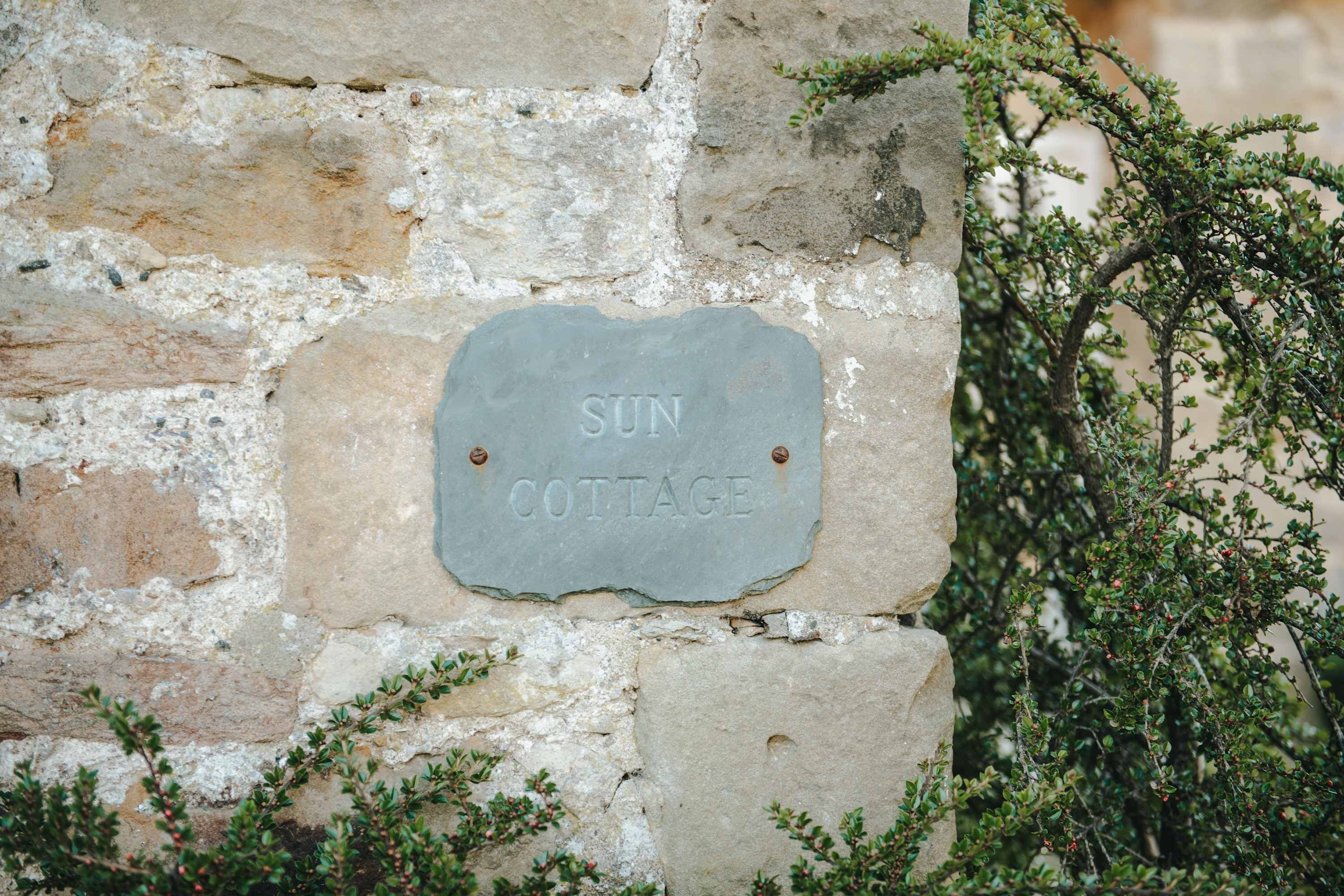 Eine Steinsäule mit einem Schild, auf dem 'SUN COTTAGE' steht.